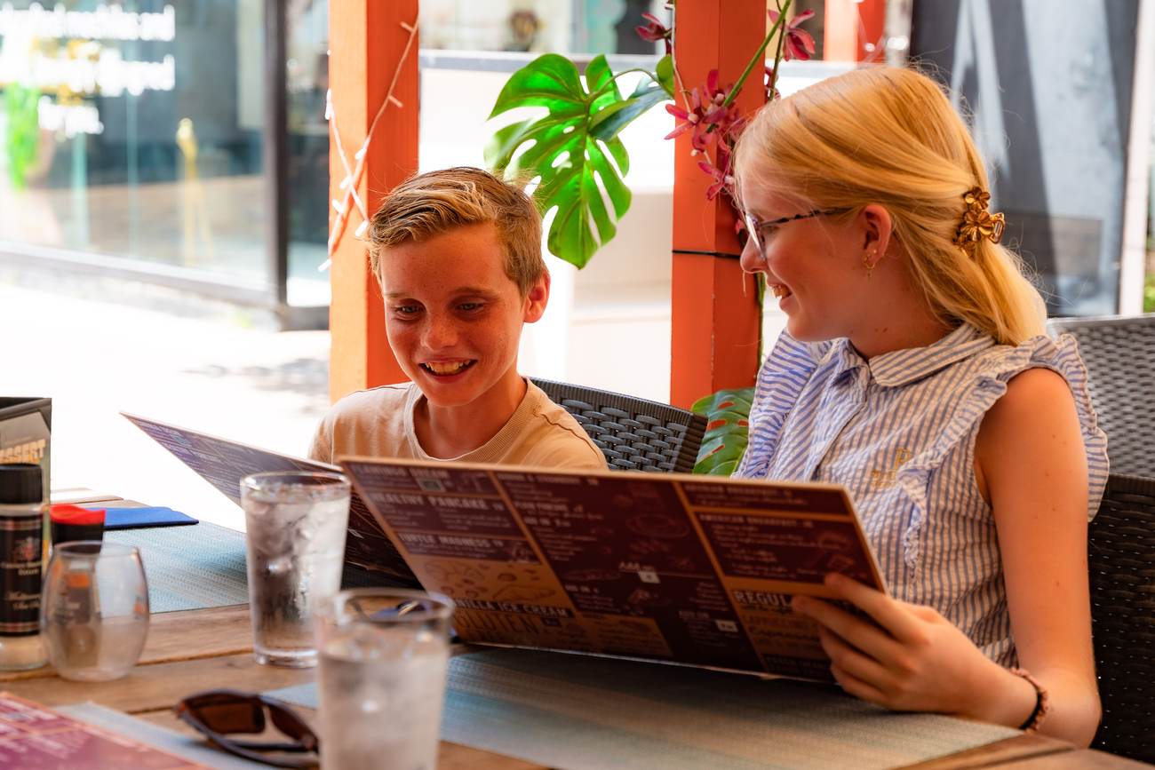 Two guests reading the Crazy Pancakes menu on the terrace