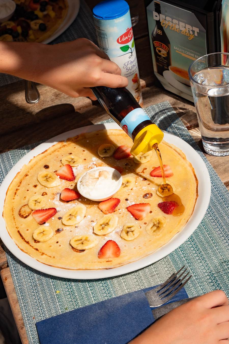 Syrup poured over a banana and strawberry Dutch pancake